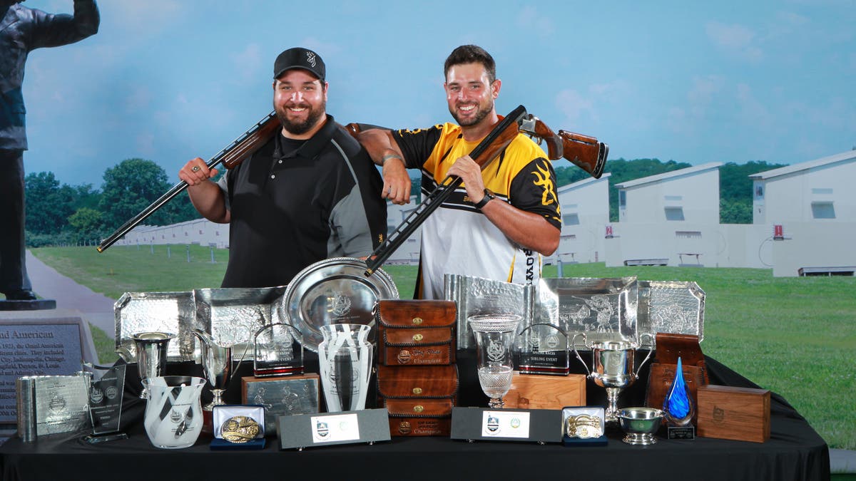 Matt and Foster Bartholow posing with Citori shotguns and dozens of trophies from the 2018 Grand American