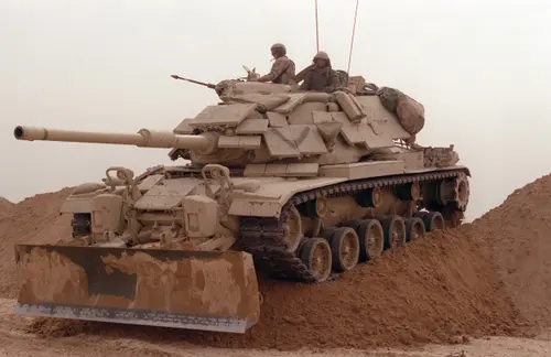 A Marine Corps M60 tank opens a breach in a defensive berm for other forces to follow during Operation Desert Storm.