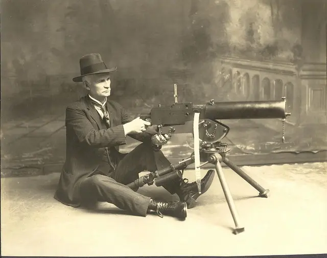 John M. Browning poses with his early water-cooled Model 1917 .30 caliber machine gun.