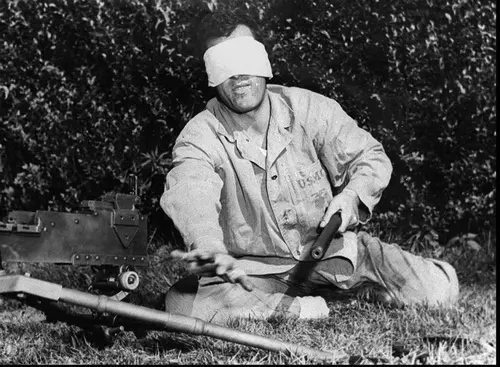 Sgt. John Basilone demonstrates how to change barrels on a Browning machine gun by feel.