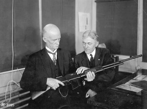 John M. Browning holding and inspecting BAR rifle.