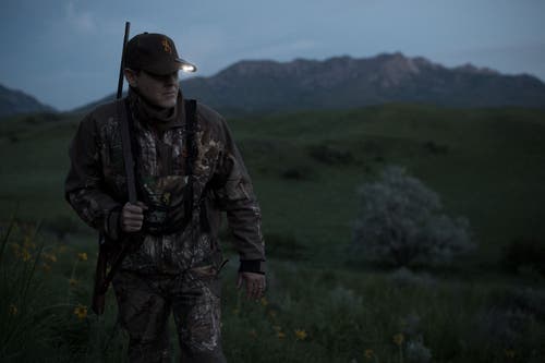 Hunter hiking at daybreak with cap light on hat.