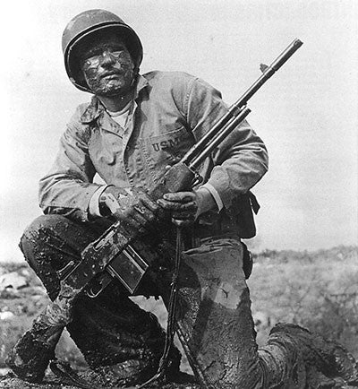 This World War II photograph shows a mud-encrusted U.S. Marine who has a World War I vintage BAR rifle. 