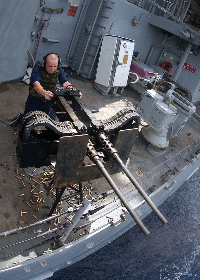 A US Navy seaman in live-fire training on twin .50 caliber Browning machine guns.