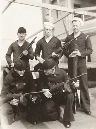 The sailor standing at far left holds a Browning designed Model 1897 riot shotgun, while the sailor standing next to him has a Browning Automatic Rifle.