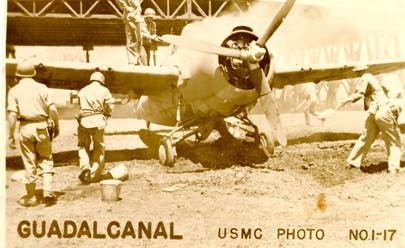 Marines rally to put out the flames on an F4F Wildcat hit by enemy fire at Henderson Field.