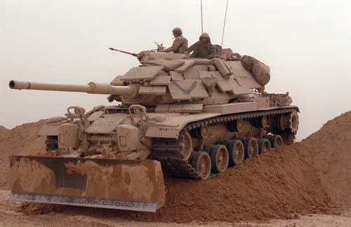 A Marine Corps M60 tank opens a breach in a defensive berm for other forces to follow during Operation Desert Storm.
