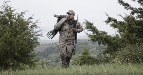 Hunter with turkey and shotgun over shoulders